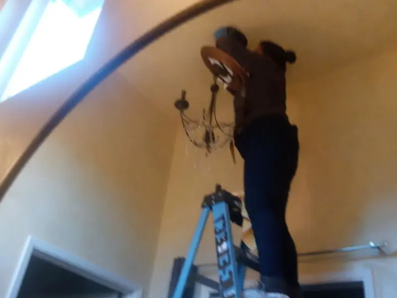 Electrician installing a chandelier in a Caroline residence